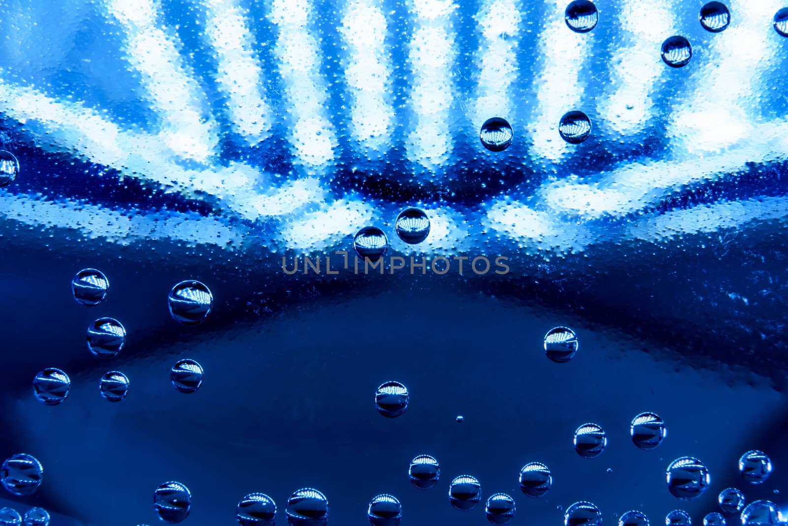 Macro shot of water with bubbles inside a plastic bottle with light and colors effects