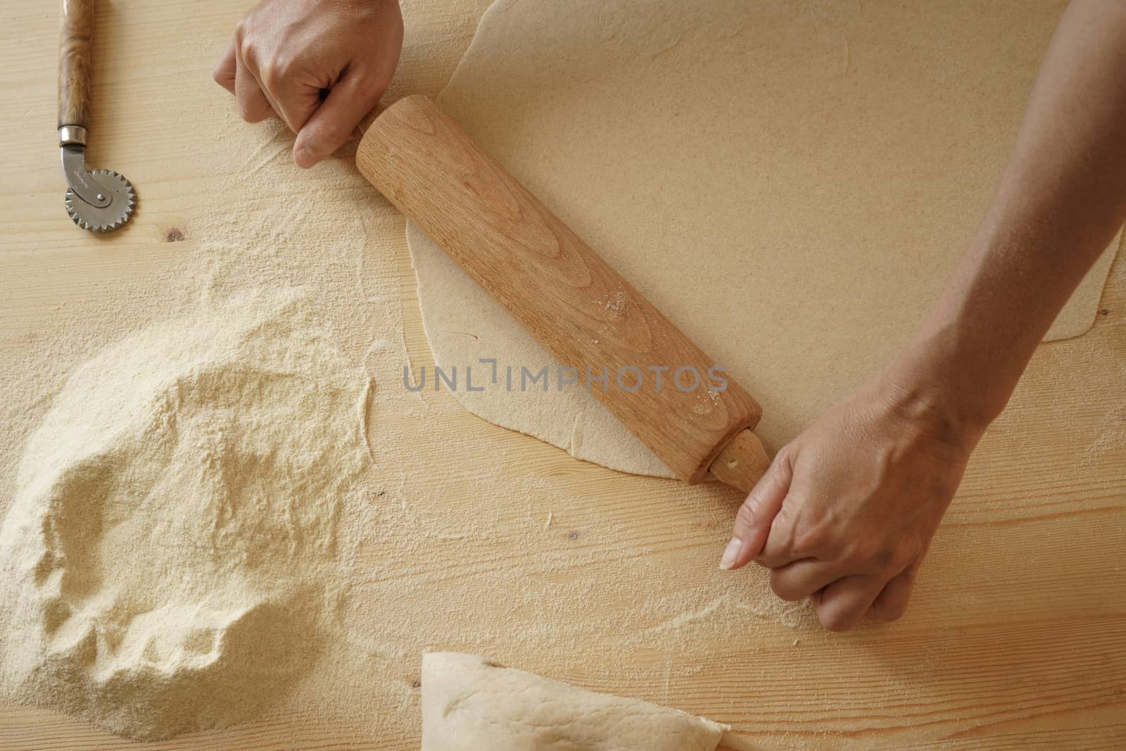 Close up process of homemade vegan farfalle pasta with durum wheat flour. The cook uses a rolling pin to stretch the dough, traditional Italian pasta, the woman cooks the food in the kitchen