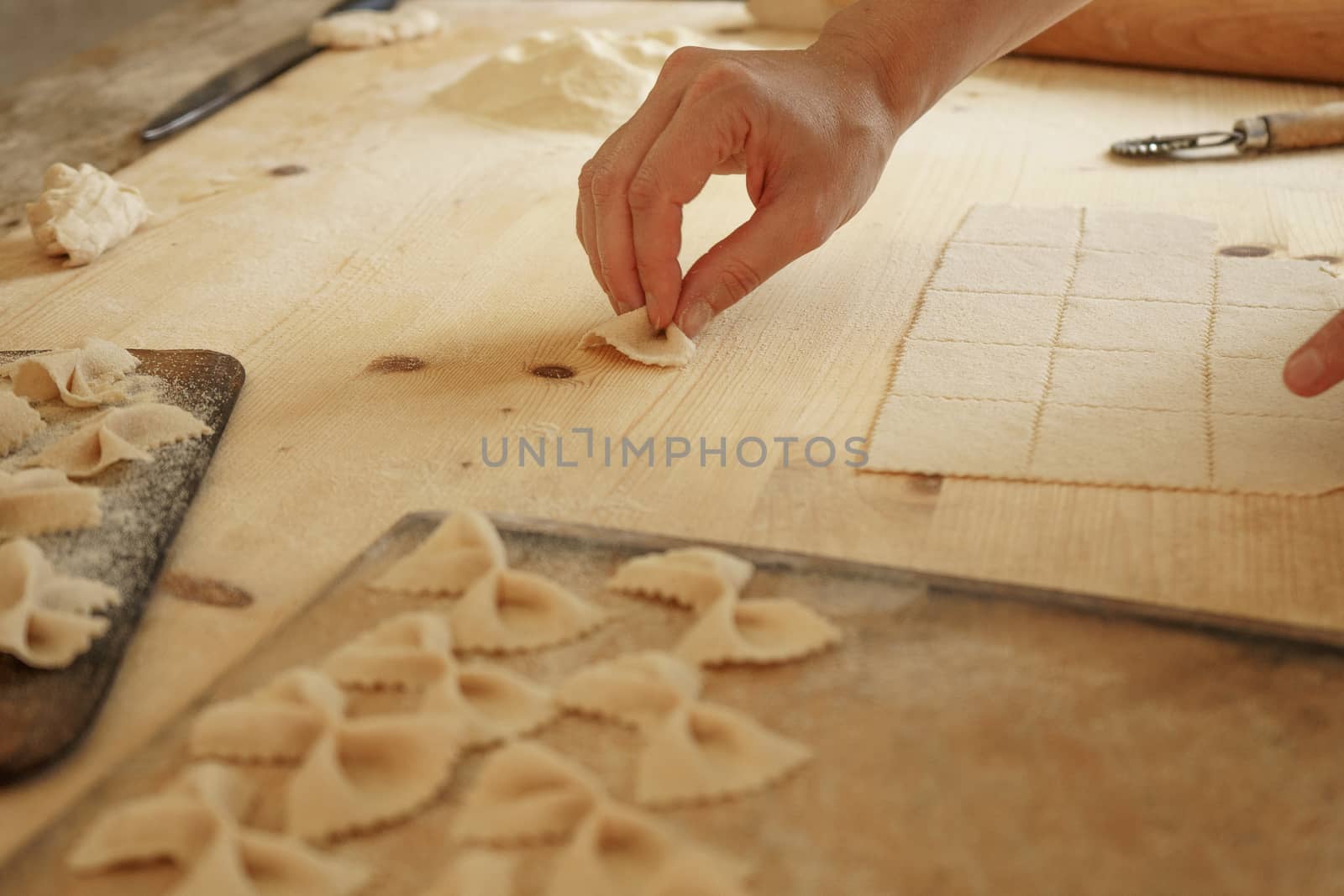 Close up process of homemade vegan farfalle pasta with durum wheat flour. The cook shapes the dough on the wooden cutting board, traditional Italian pasta, the woman cooks the food in the kitchen