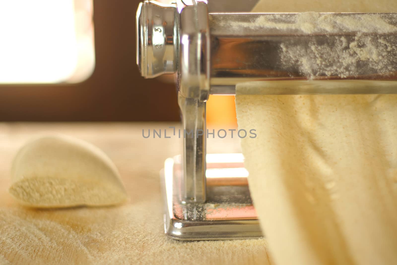 Making homemade fresh pasta: backlit close up of the details of the pasta rolled out by the metal manual pasta machine by robbyfontanesi