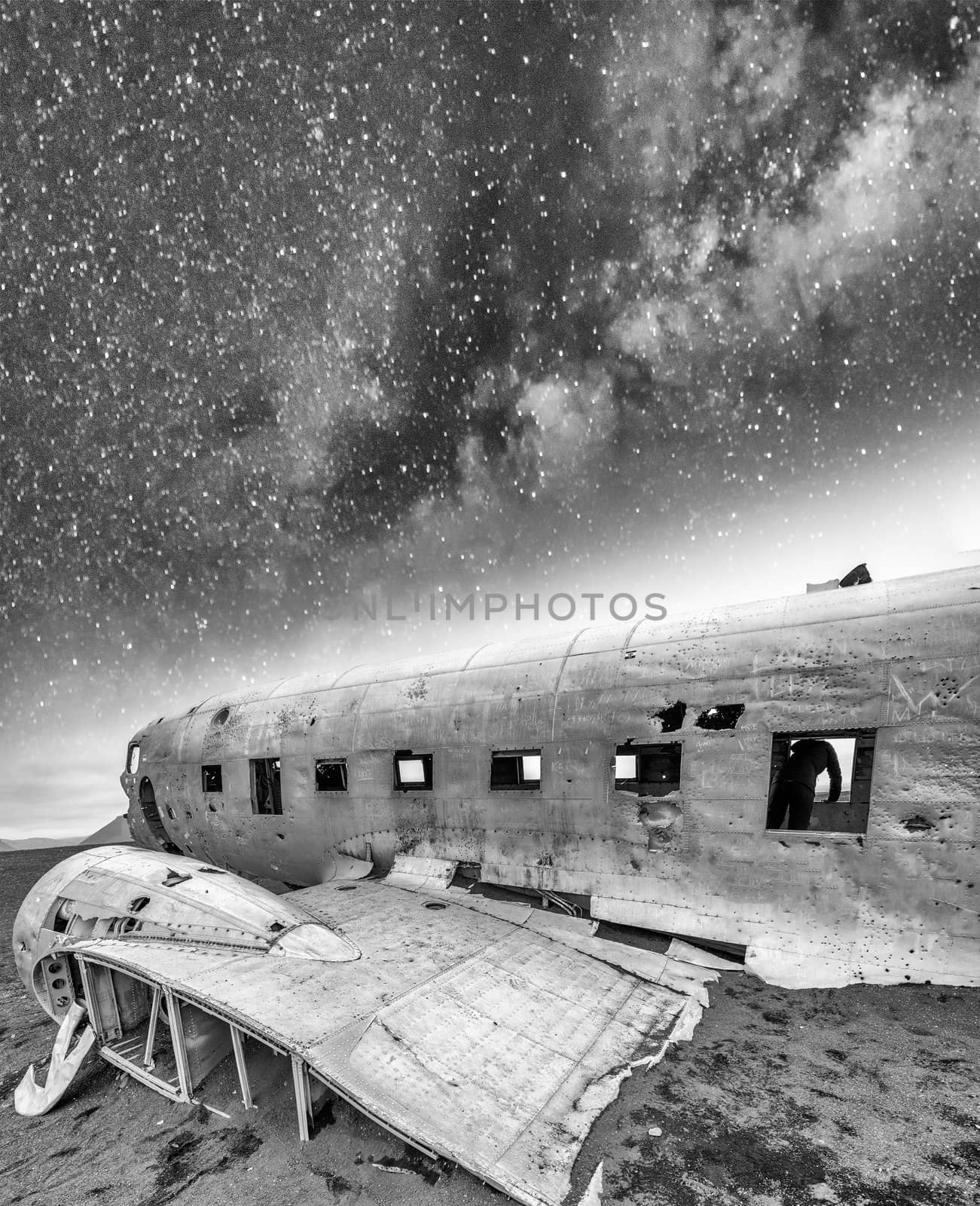 Abandoned wreckage of old aircraft on a beach under a starry nig by jovannig