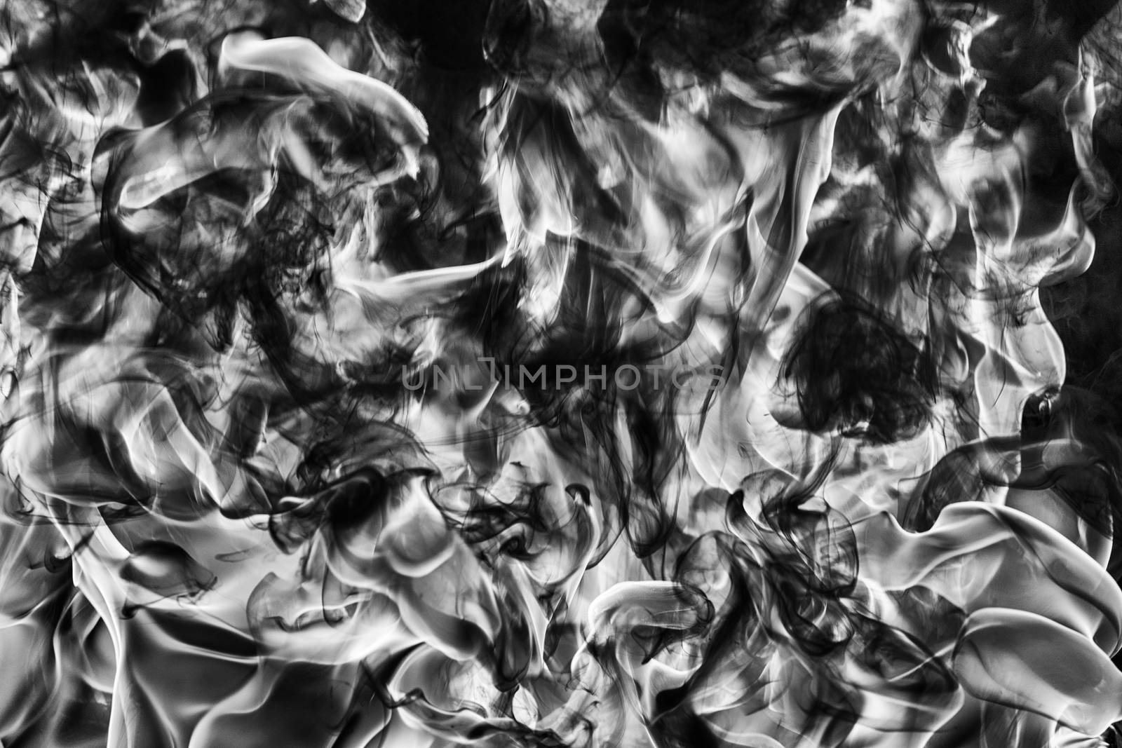Abstract puffs of natural black smoke and white huge flame of strong fire. Black and white photography, motion blur from fire, high temperature from flames. Dangerous firestorm abstract background.