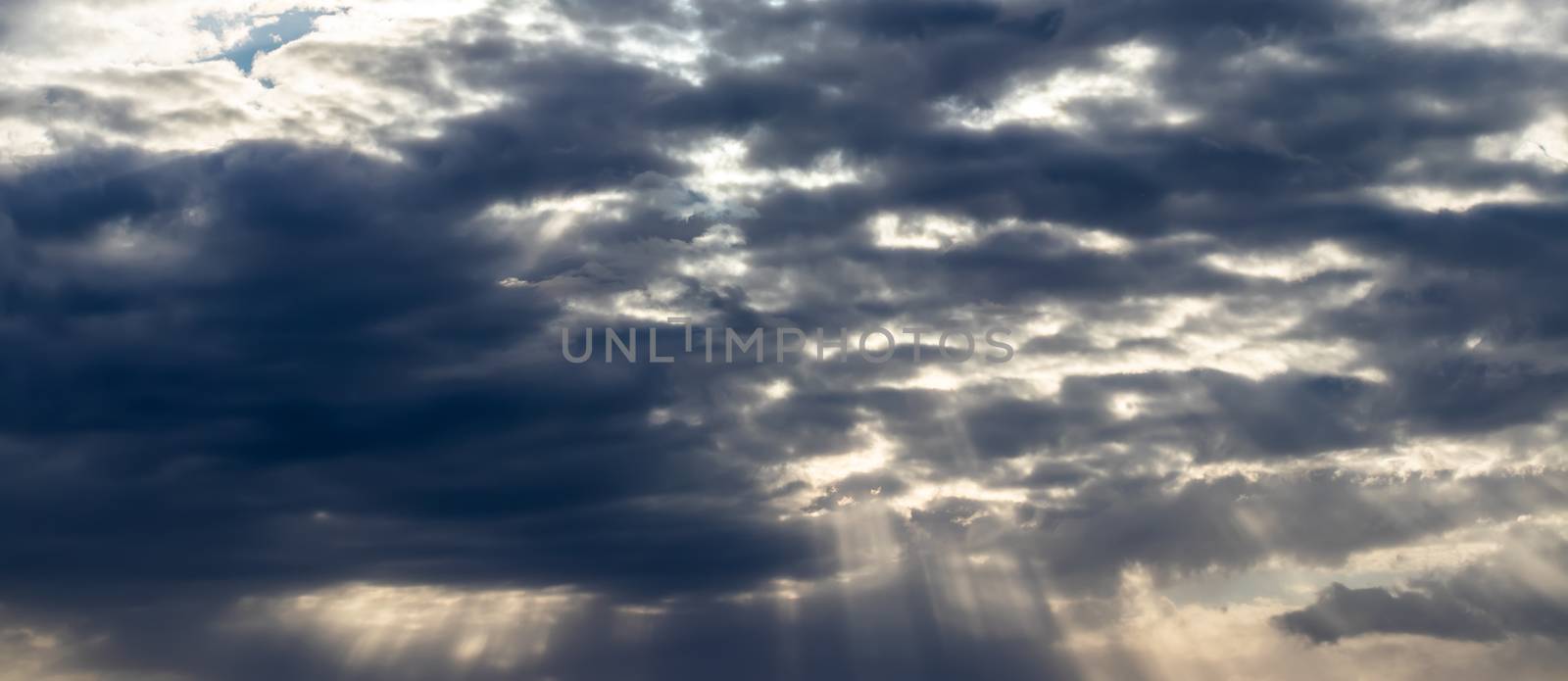 Sun rays breaking through cumulus clouds. The concept of divine light, a glimmer of hope or overcoming difficulties. Spiritual religious abstract background.