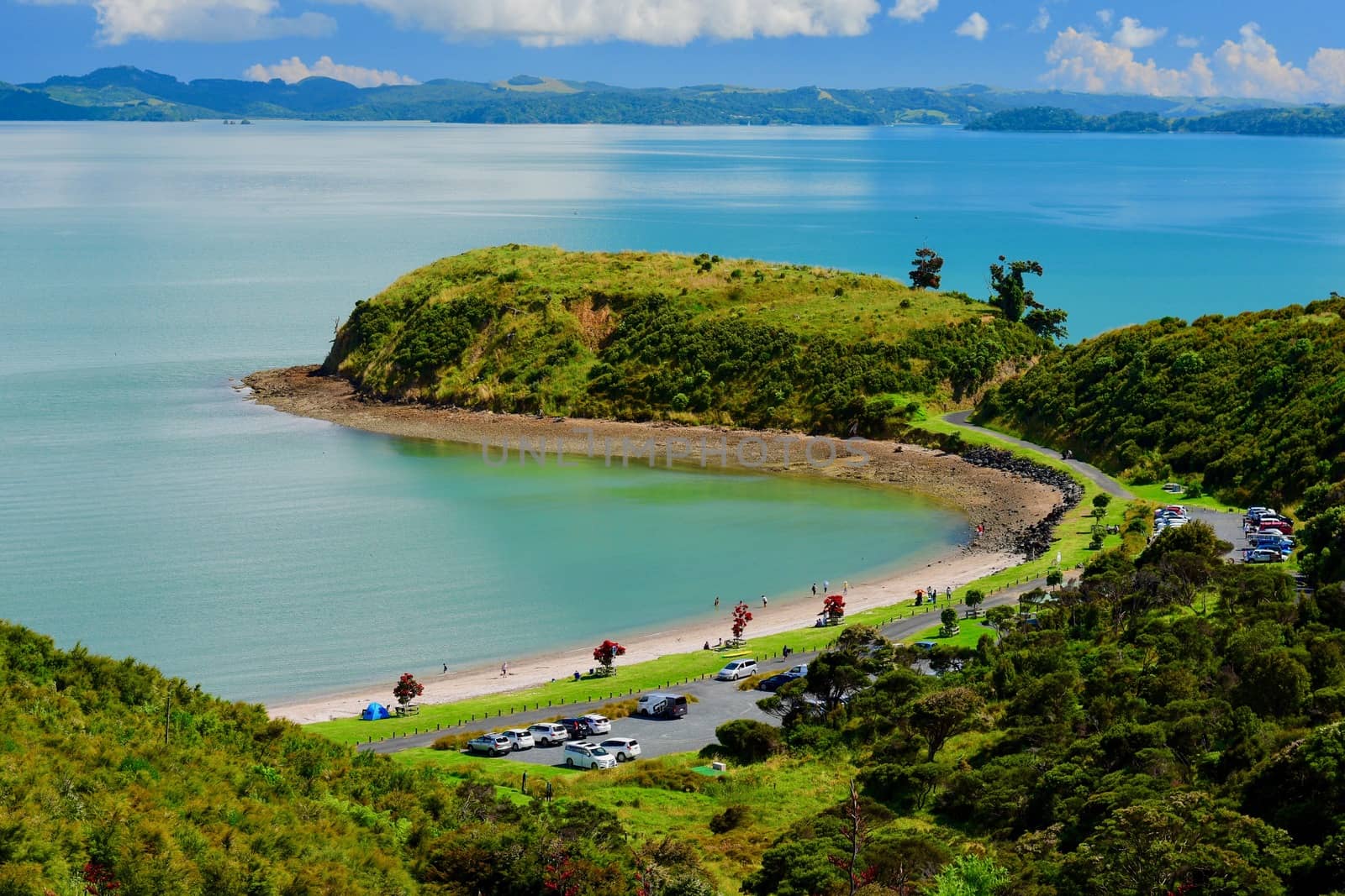 beautiful seascape, bright blue ocean, and some people very far away enjoying water activities.