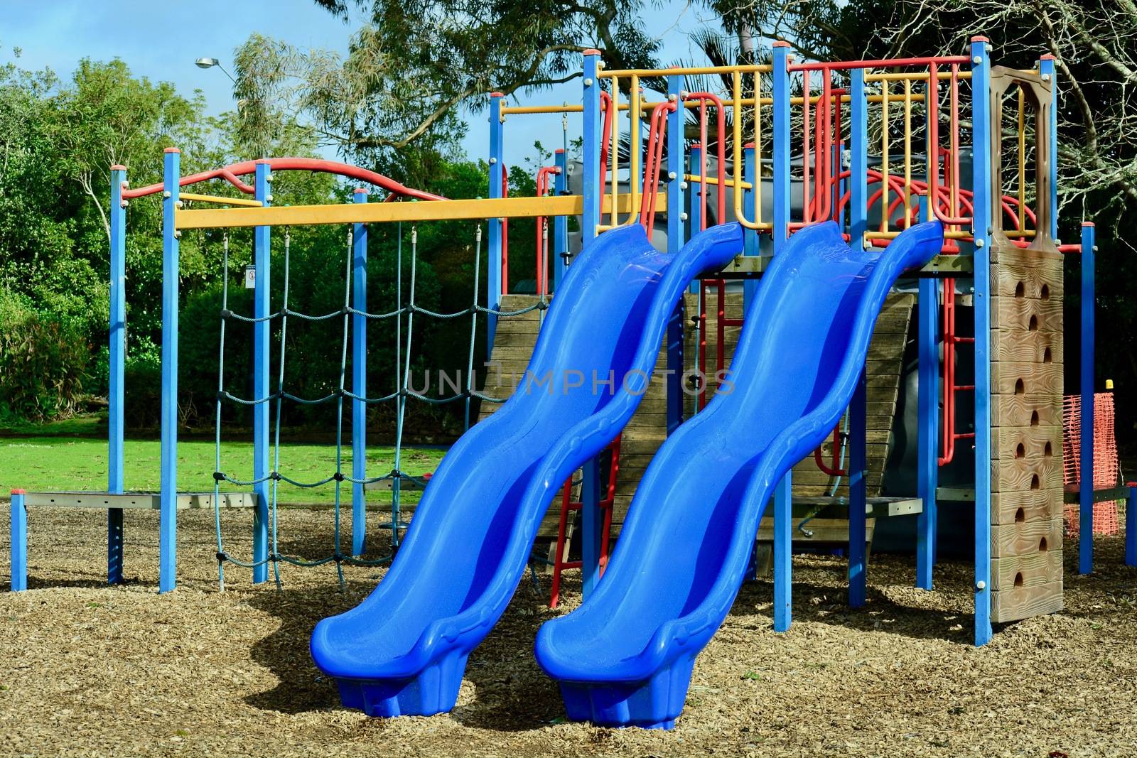 A colourful playground, inviting kids to play there. Combination playground structure for small children including slides, climbers, playhouse by Marshalkina