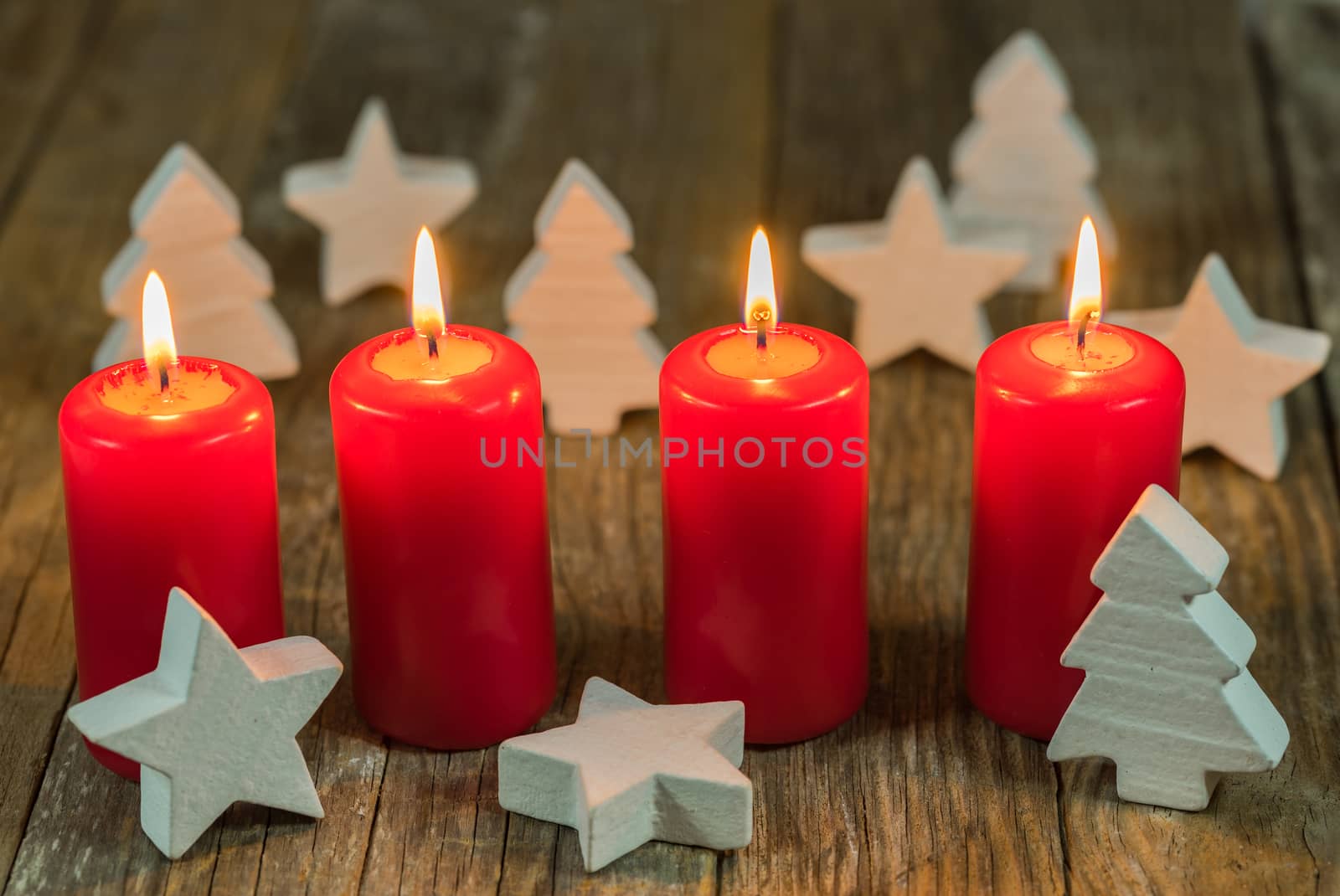 Christmas or advent four red burning candles with stars and trees decoration