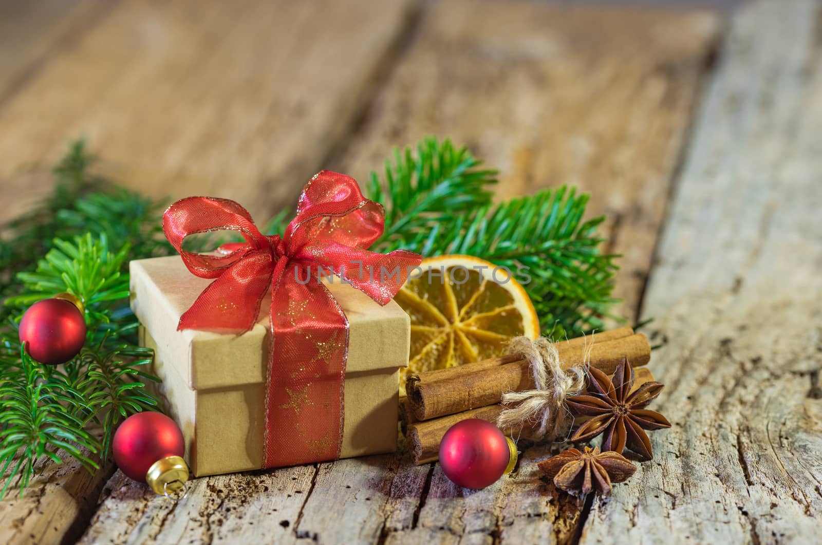 Christmas present with red ribbon and natural decorations on wood background