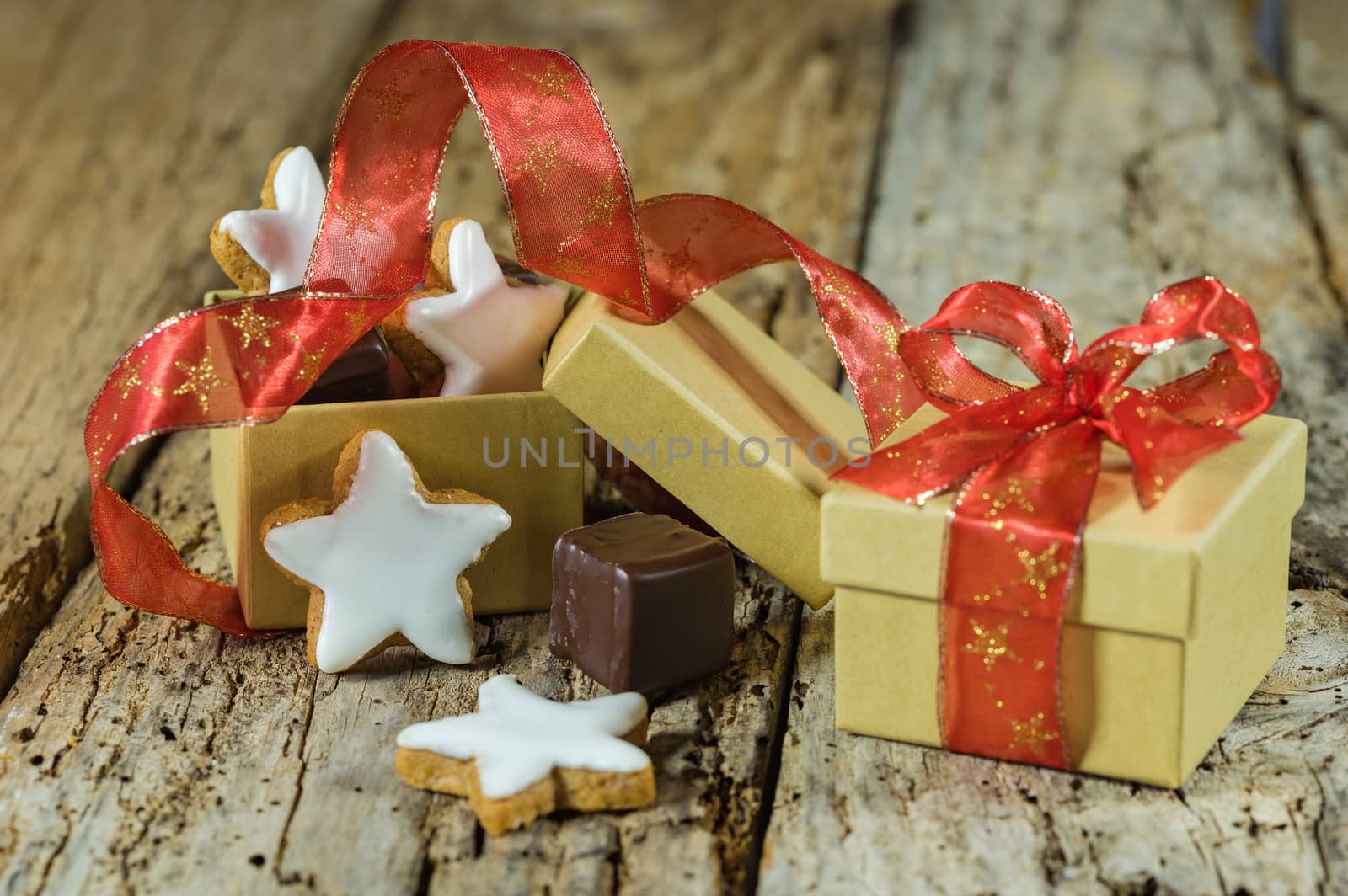 Christmas star biscuits and chocolate gift with red ribbon on wooden table