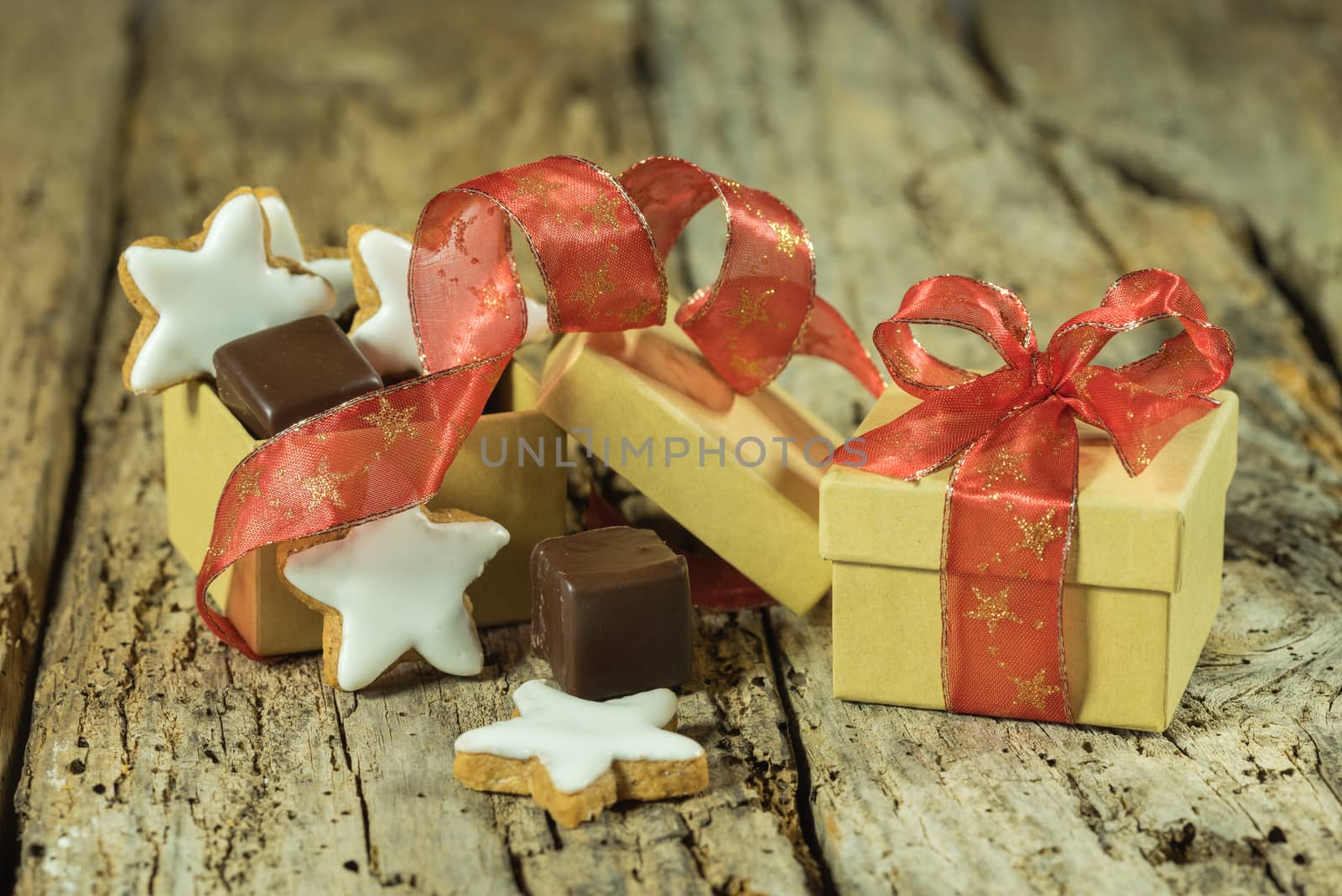 Christmas pastry and chocolate in gift box with red ribbon on wooden table