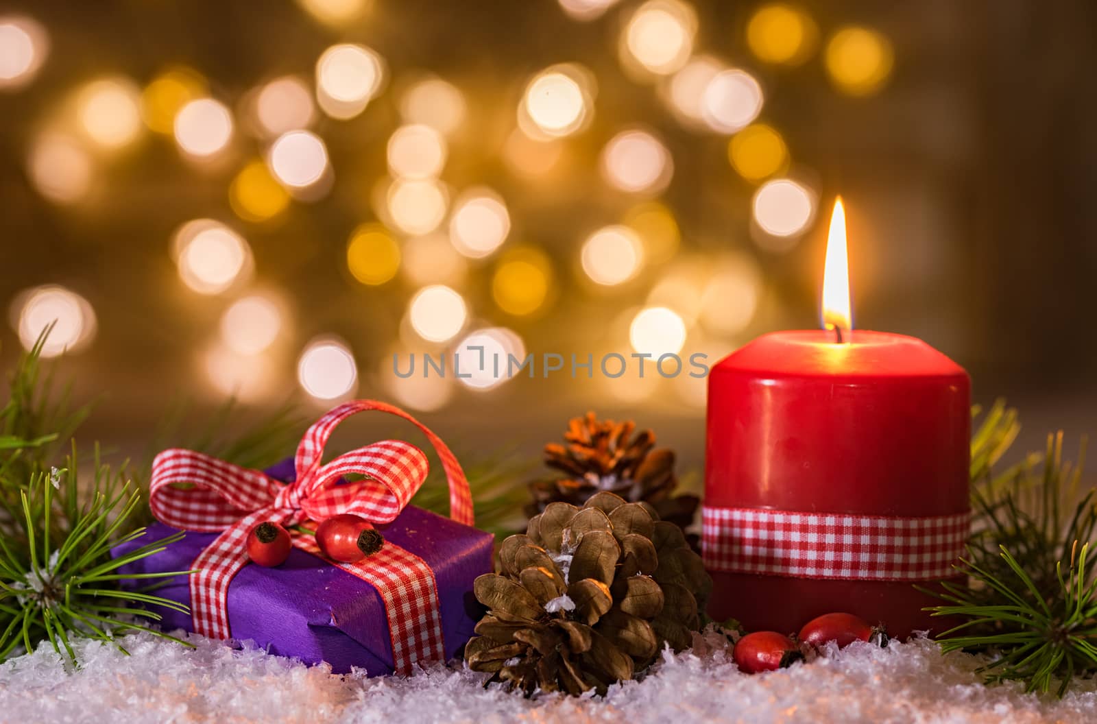 Christmas candle and gift box on snow with lights background