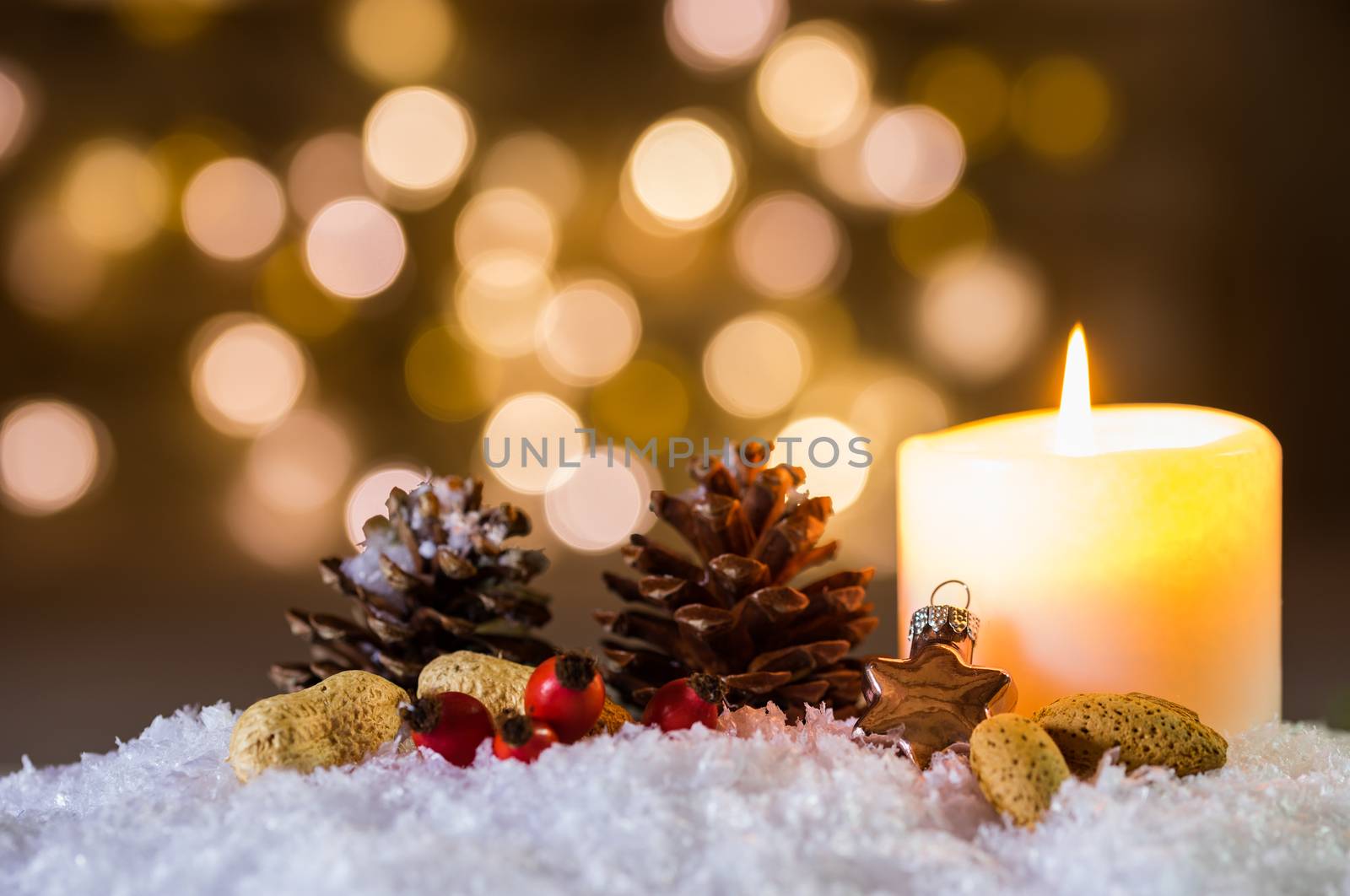 Advent or Christmas candle with ornaments decoration on snow and blurred lights background