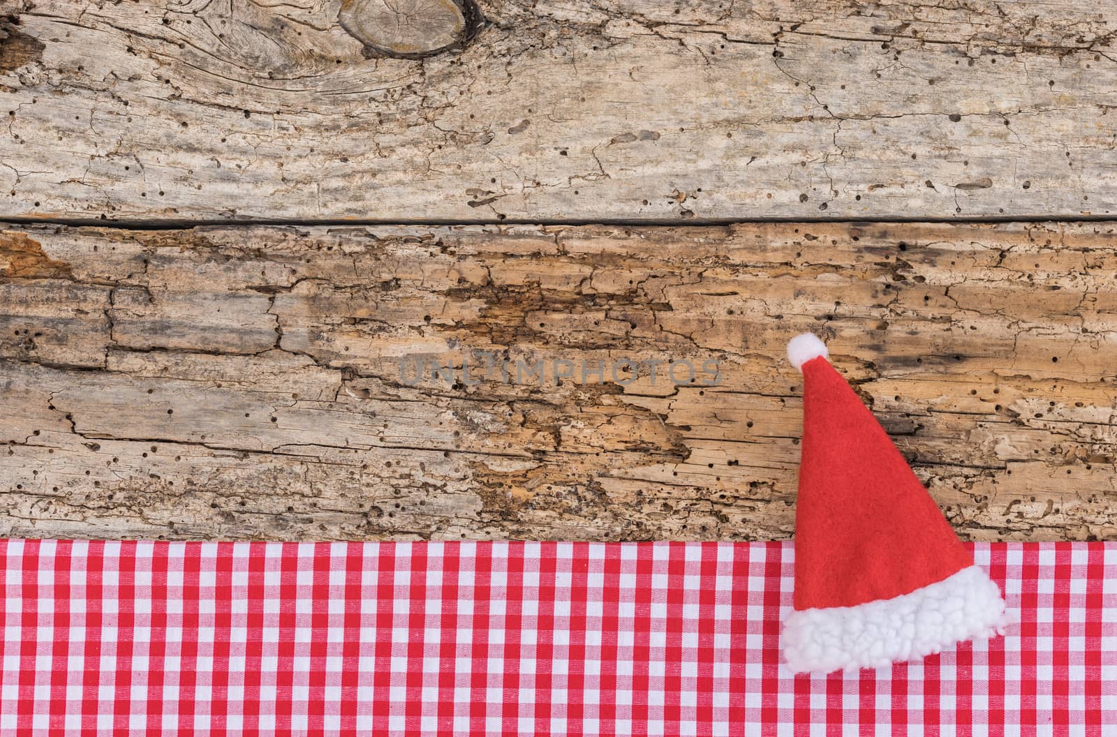 Christmas background with Santa Claus cap on rustic wood, copy space