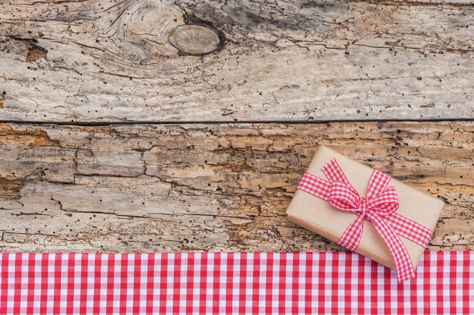 Christmas present wirth ribbon bow on old wooden table background, top view