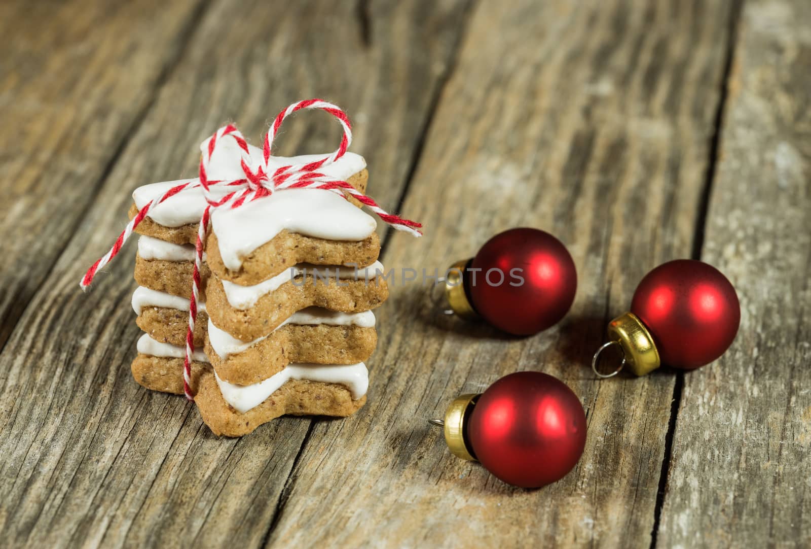 Star shaped christmas cookies stack on wooden table with red balls