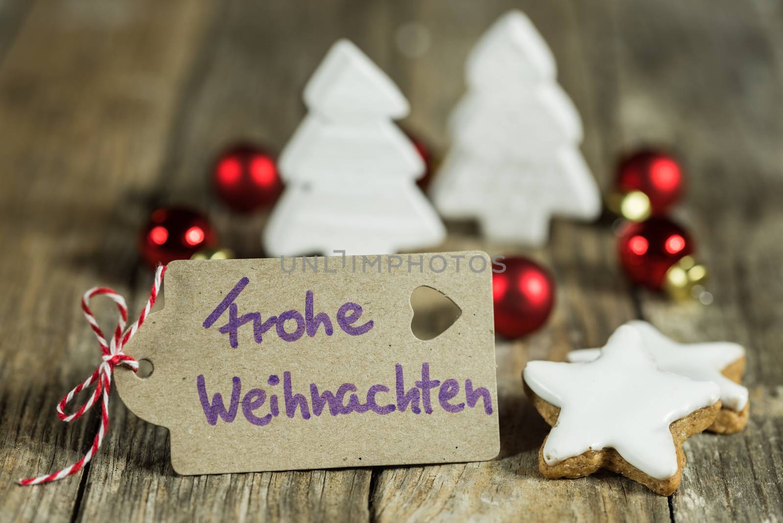 Label with handwritten greeting in german, Frohe Weihnachten, means Merry Christmas, with xmas ornaments
