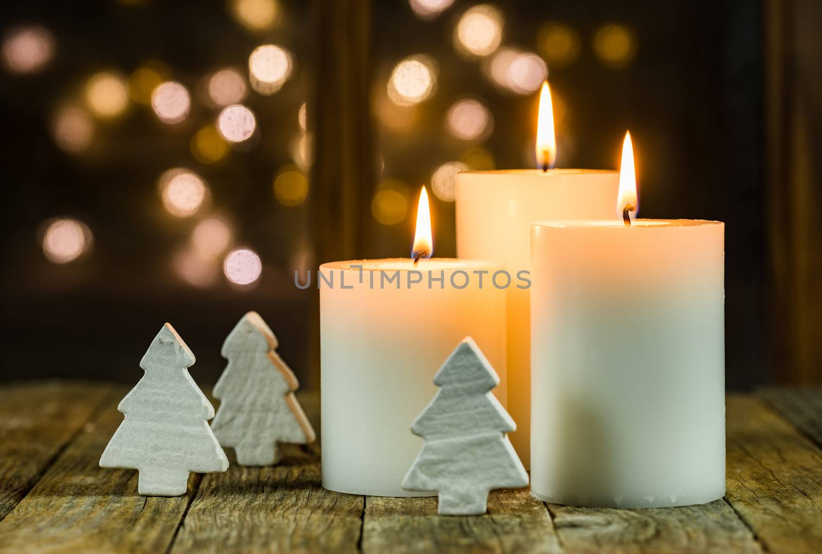 White Christmas candles with ornaments and blurred lights background