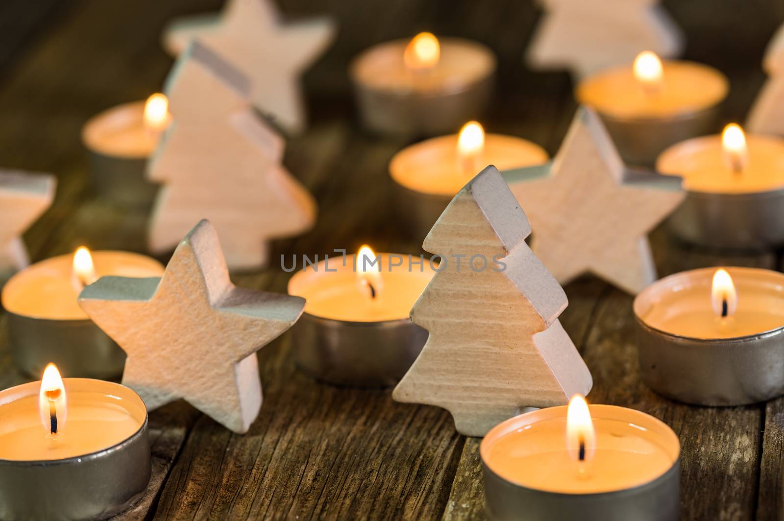 Advent candle flames with white wooden christmas ornaments