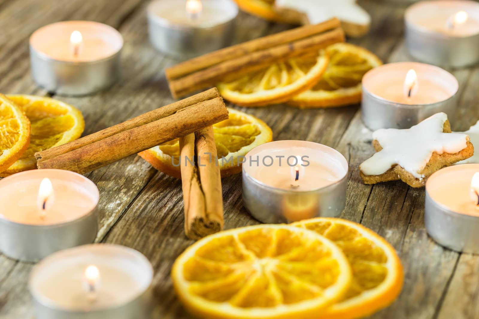Advent and Christmas decoration with burning candles, orange slices, cinnamon and star biscuits