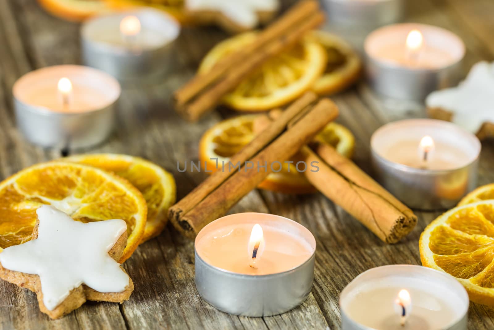 Christmas composition with candles, star shape cookies, cinnamon and orange slices