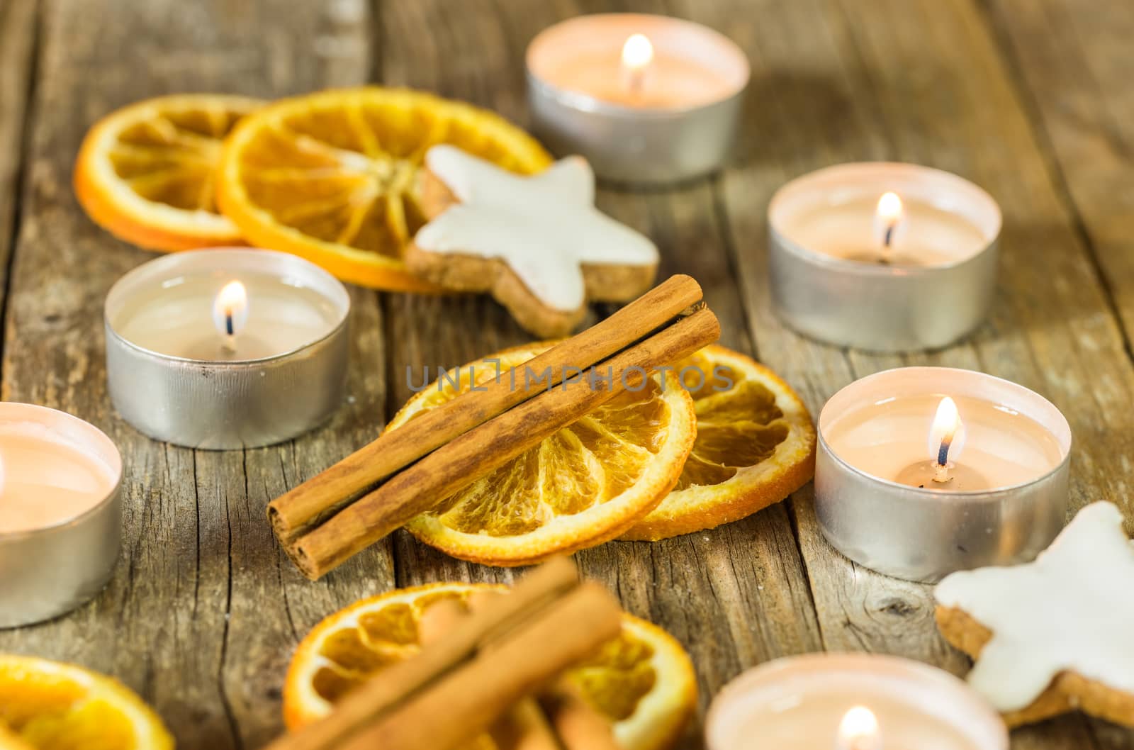 Aromatic christmas season composition with burning candles, star cookies, cinnamon and orange slices