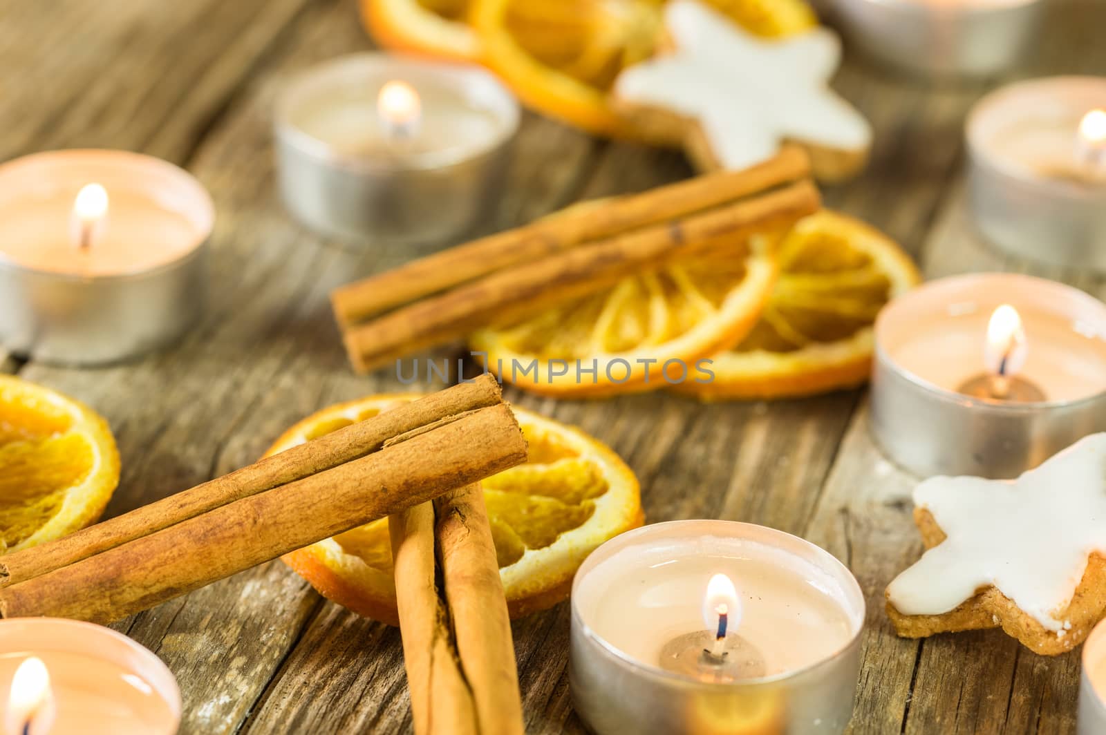 Christmas time table decoration with candle, star shape biscuit, orange slices and cinnamon spice