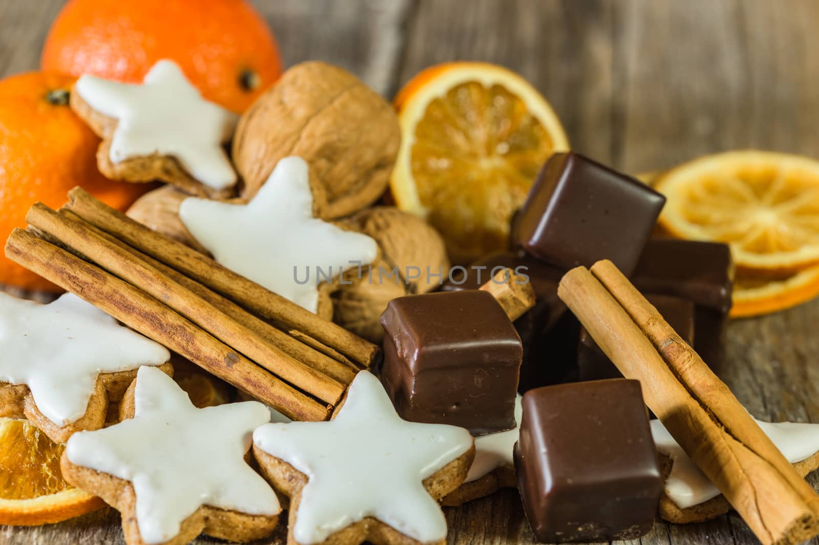 Christmas and Advent food, star cookies, chocolate, nuts, oranges, and cinnamon on wooden table