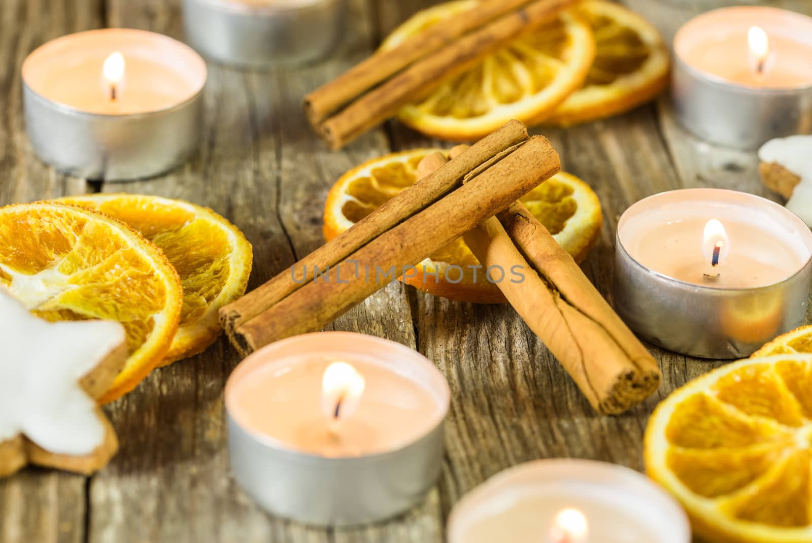 Advent and Christmas candlelights with star shape biscuit, cinnamon spice and orange slices on wooden table