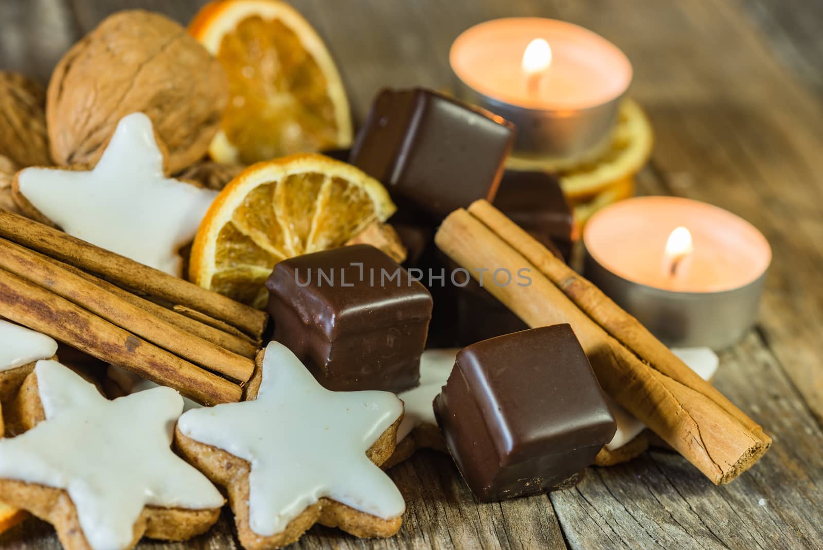 Advent and Christmas composition of star shape biscuits, chocolate, cinnamon, nuts, orange slices and candles