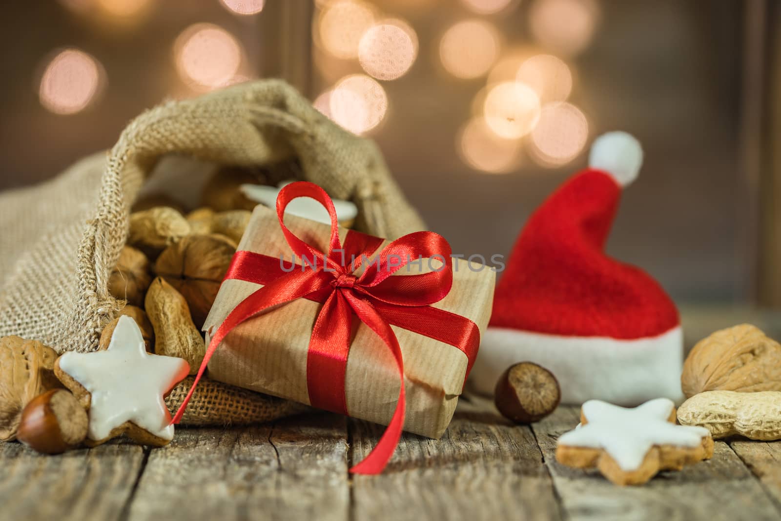 Advent and Christmas gift and santa claus bag and cap with nuts and cookies with sparkling lights background