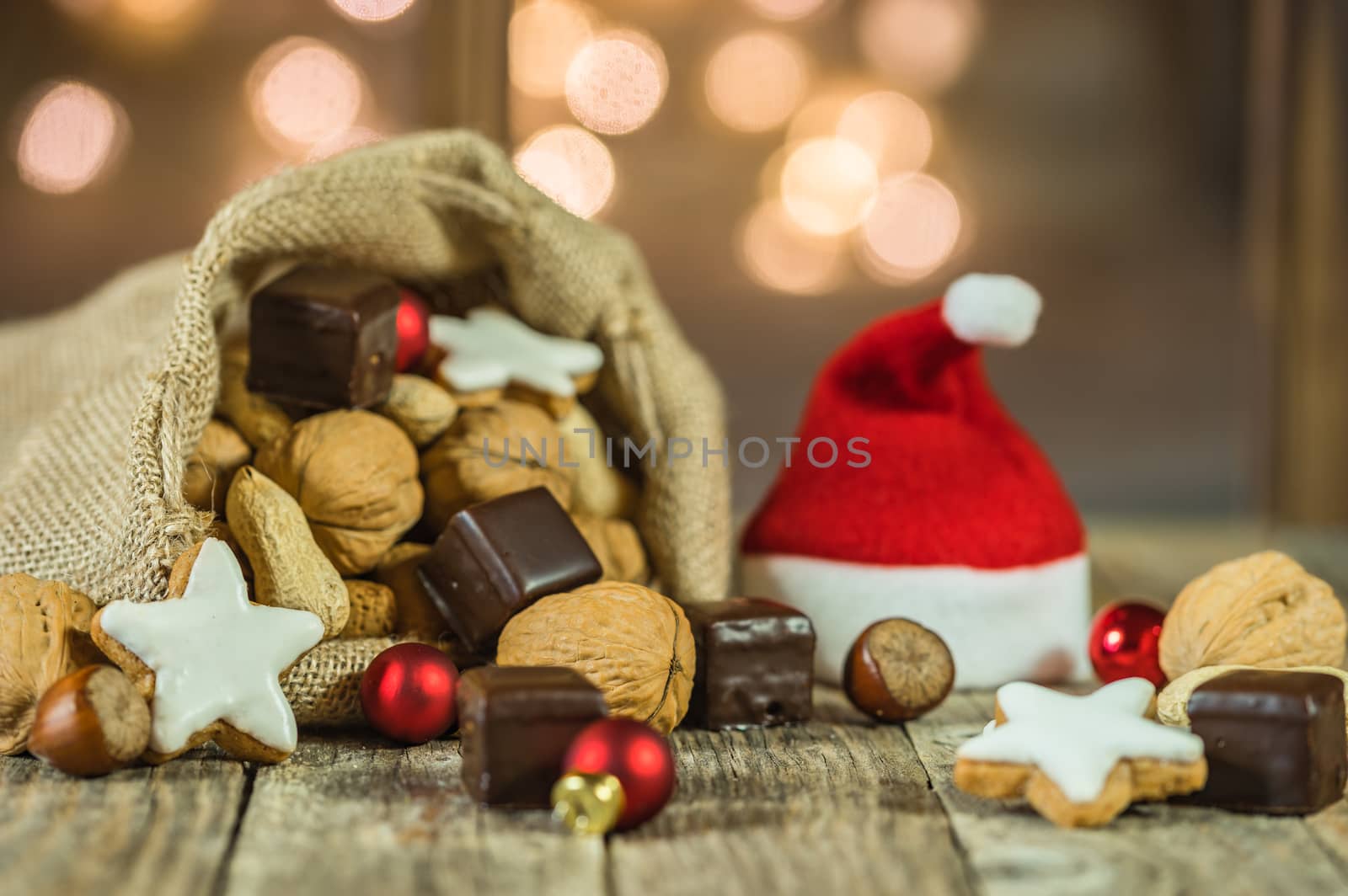 Advent and Christmas santa claus bag and cap with nuts, cookies and sparkling lights background