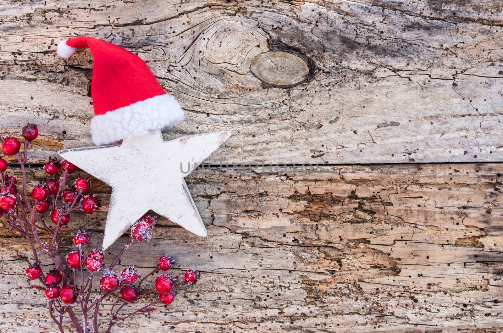 Christmas star with Santa hat and red berries on wooden background