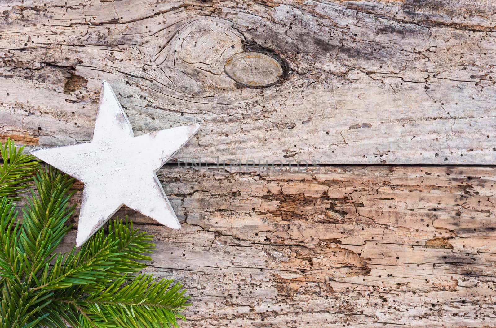 White wooden christmas star with green fir tree branch on rustic wood background, copy space