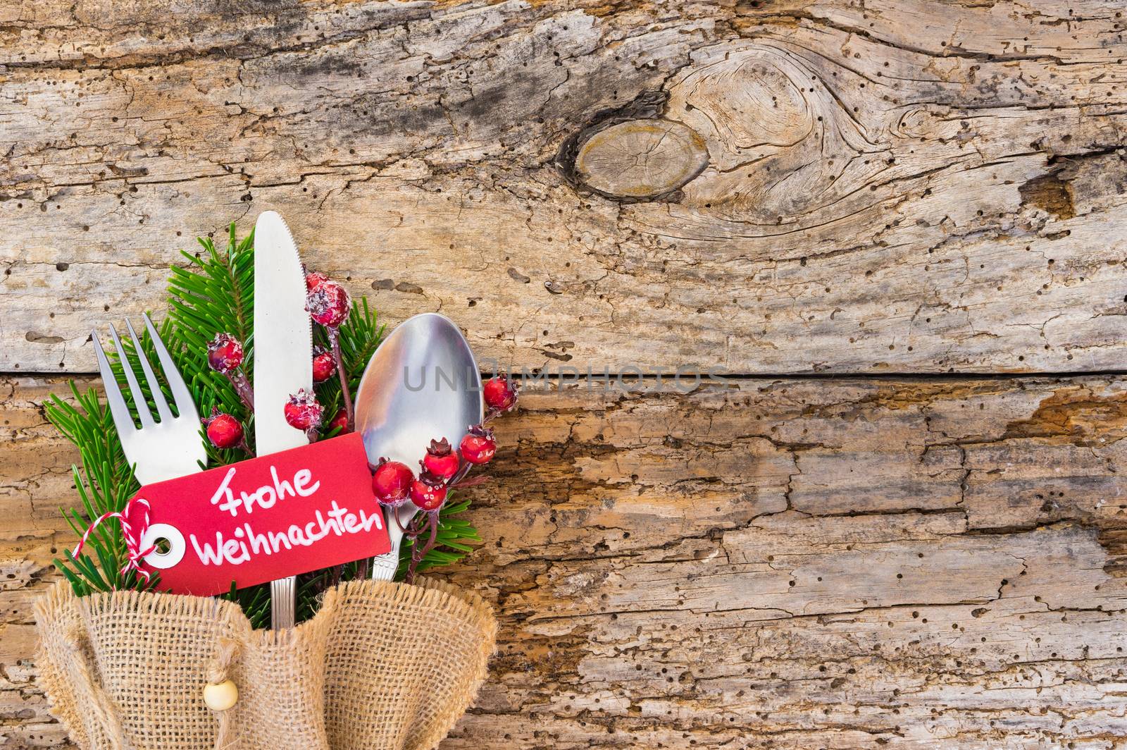 Christmas cutlery on wooden table background with german label text, Frohe Weihnachten, means Merry Christmas 