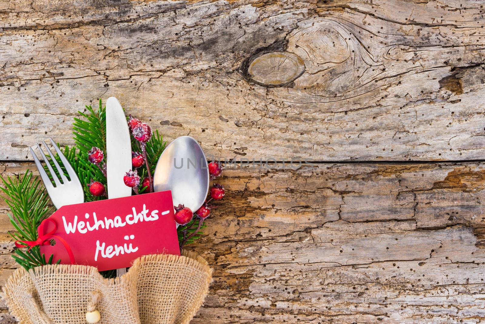 Christmas dinner place setting with label an german text, Weihnachts-Menue, means christmas menu, on rustic wooden table