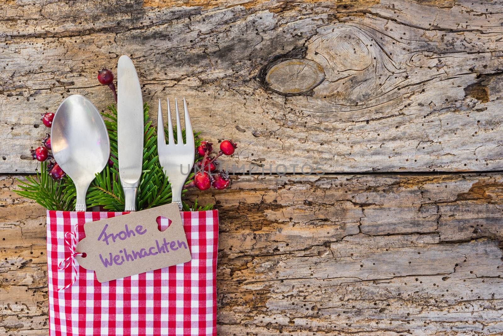 Christmas cutlery on wooden table background with german label text, Frohe Weihnachten, means Merry Christmas 