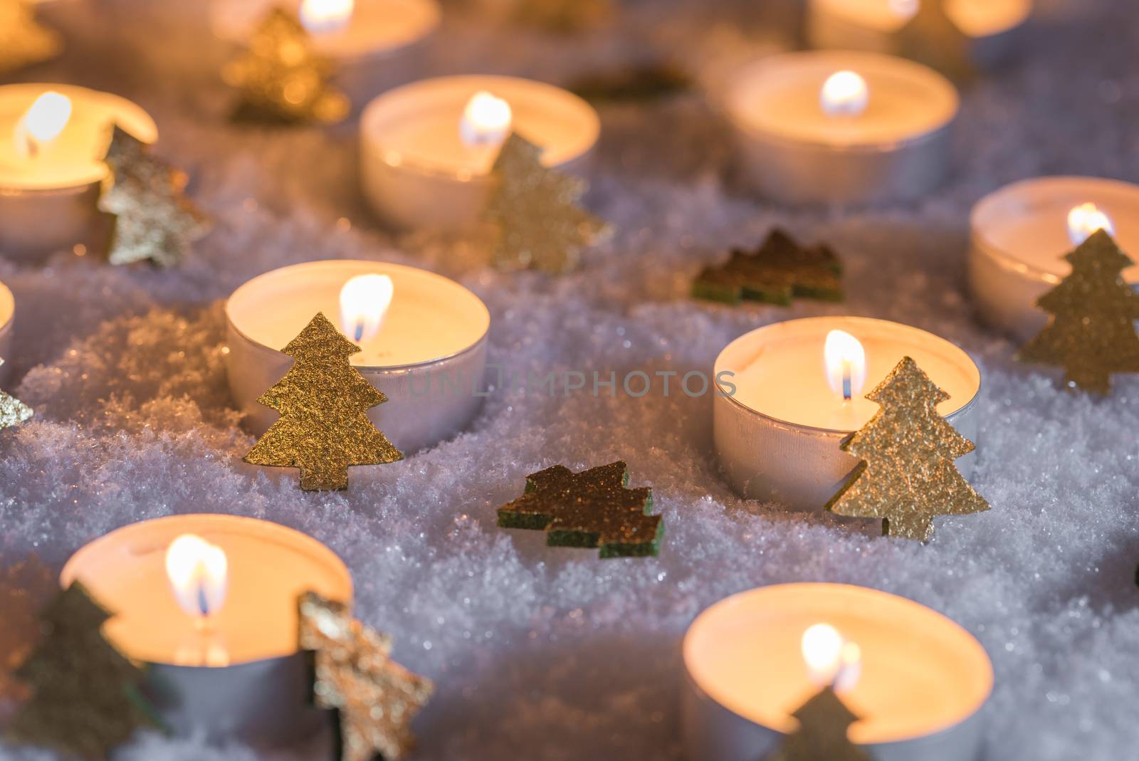 Advent and Christmas time candle flames with golden xmas trees decoration on snow