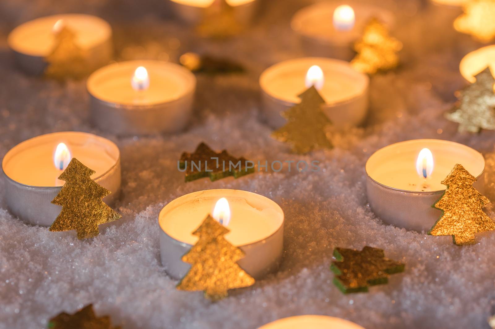 Advent and Christmas time candle flames with golden xmas trees decoration on snow by Vulcano