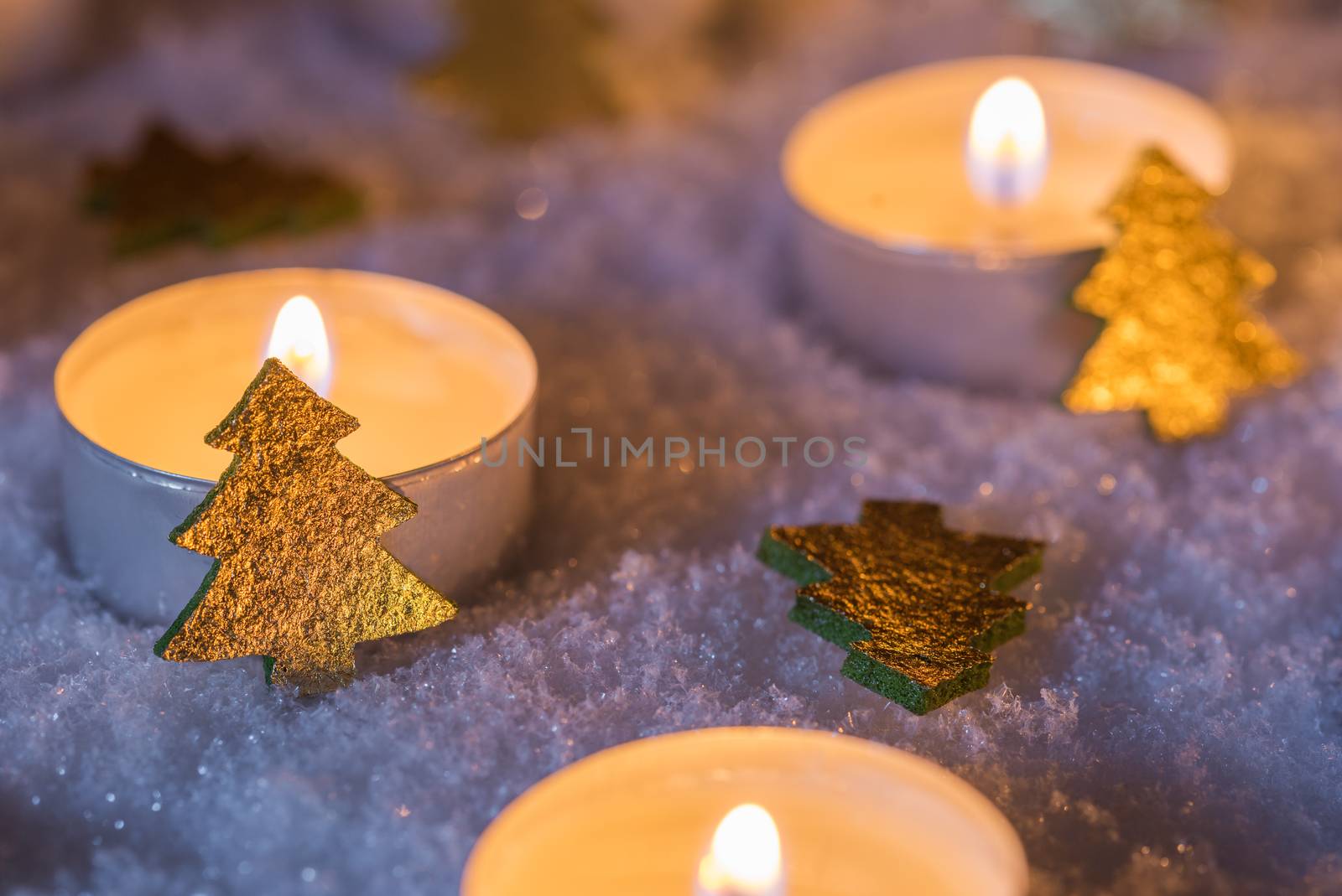 Advent and Christmas candle flames with golden christmas trees on white snow by Vulcano