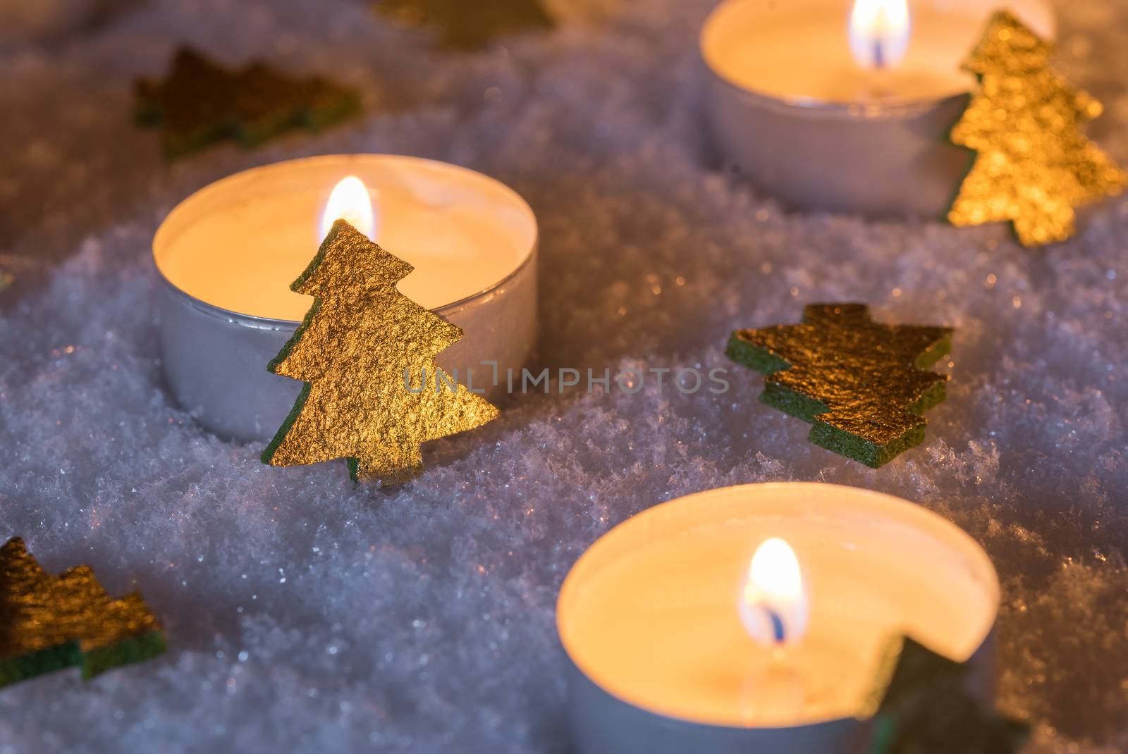 Advent and christmas candlelights with golden shiny christmas trees on white snow by Vulcano