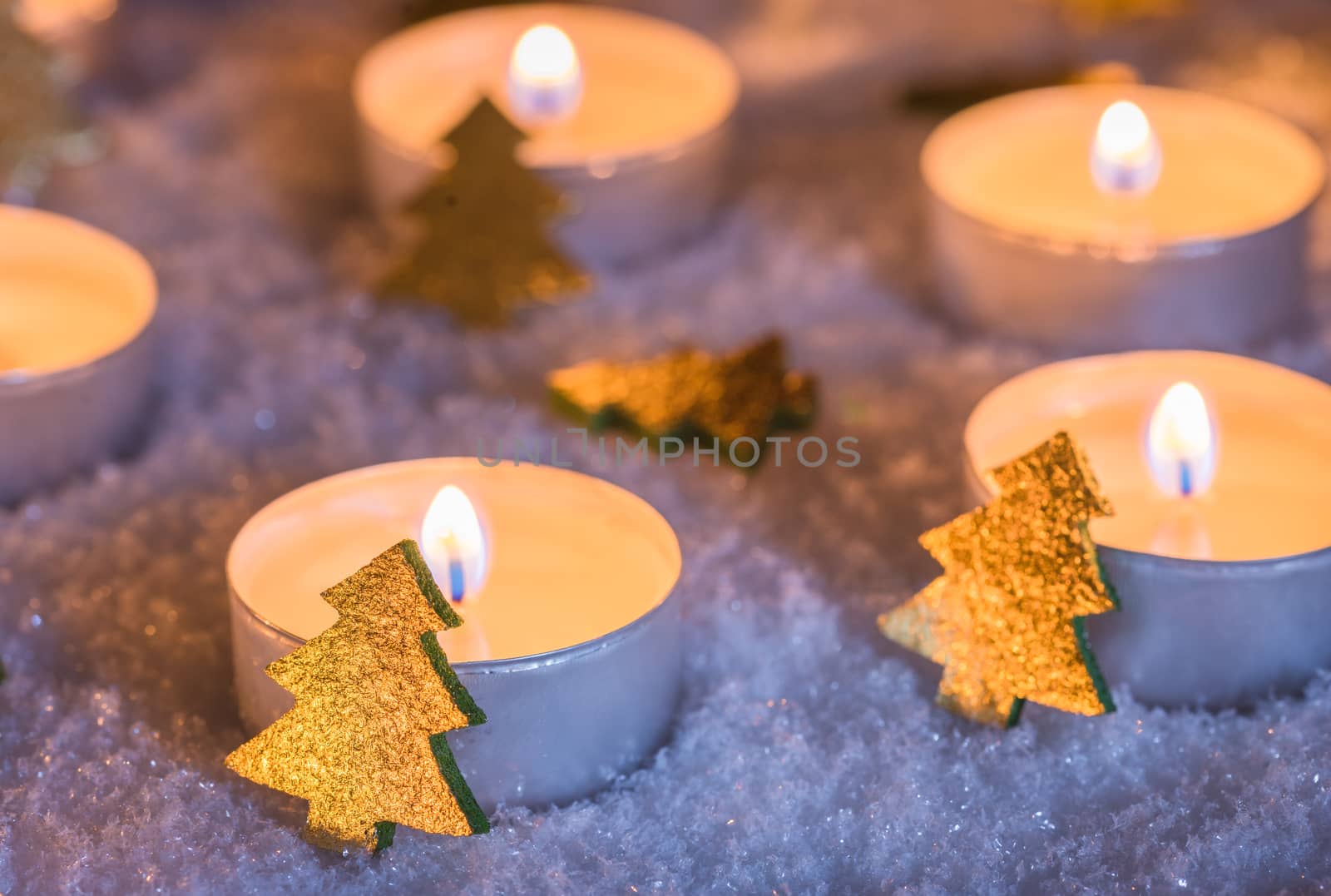 Festive christmas candle flames with golden ornaments on white snow at night by Vulcano