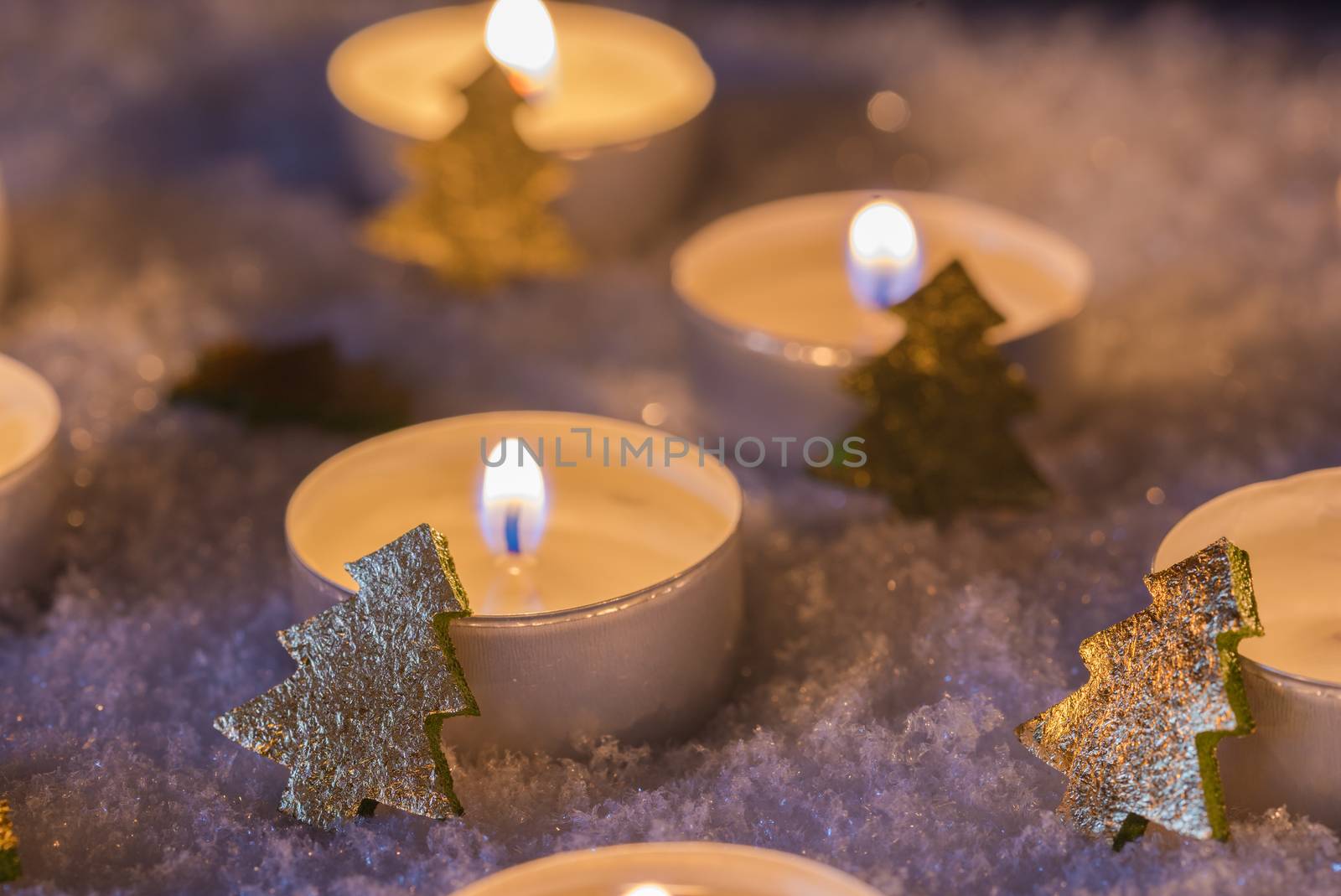 Christmas atmosphere with candlelights and ornaments on snow in the dark 