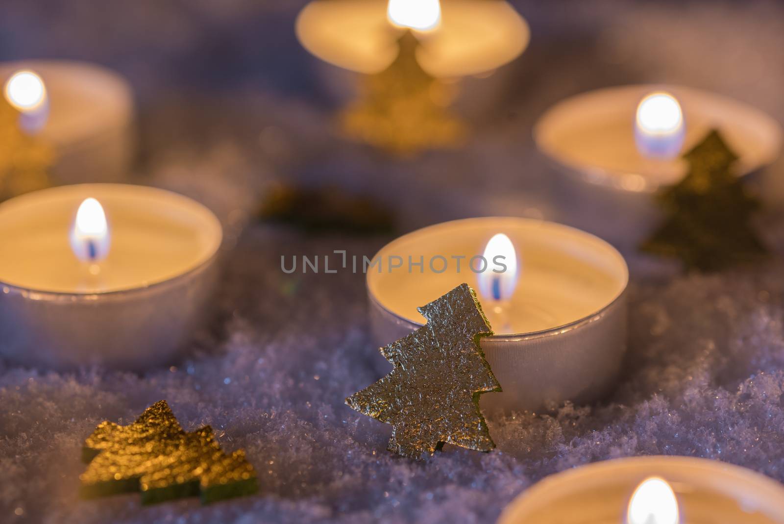 Christmas and Advent candle flames with golden ornaments on snow