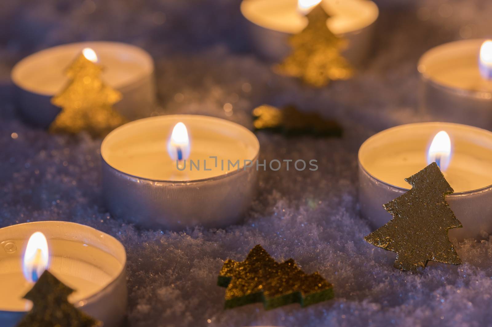 Christmas and Advent candle flames with golden ornaments on snow by Vulcano