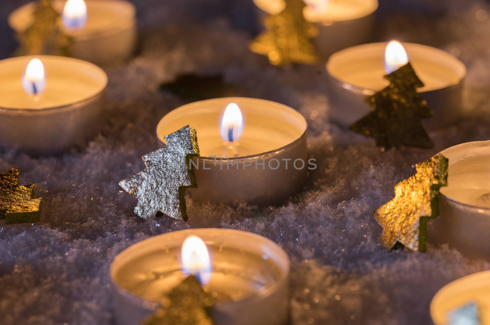 Advent decoration with candlelight and golden christmas trees on snow by Vulcano