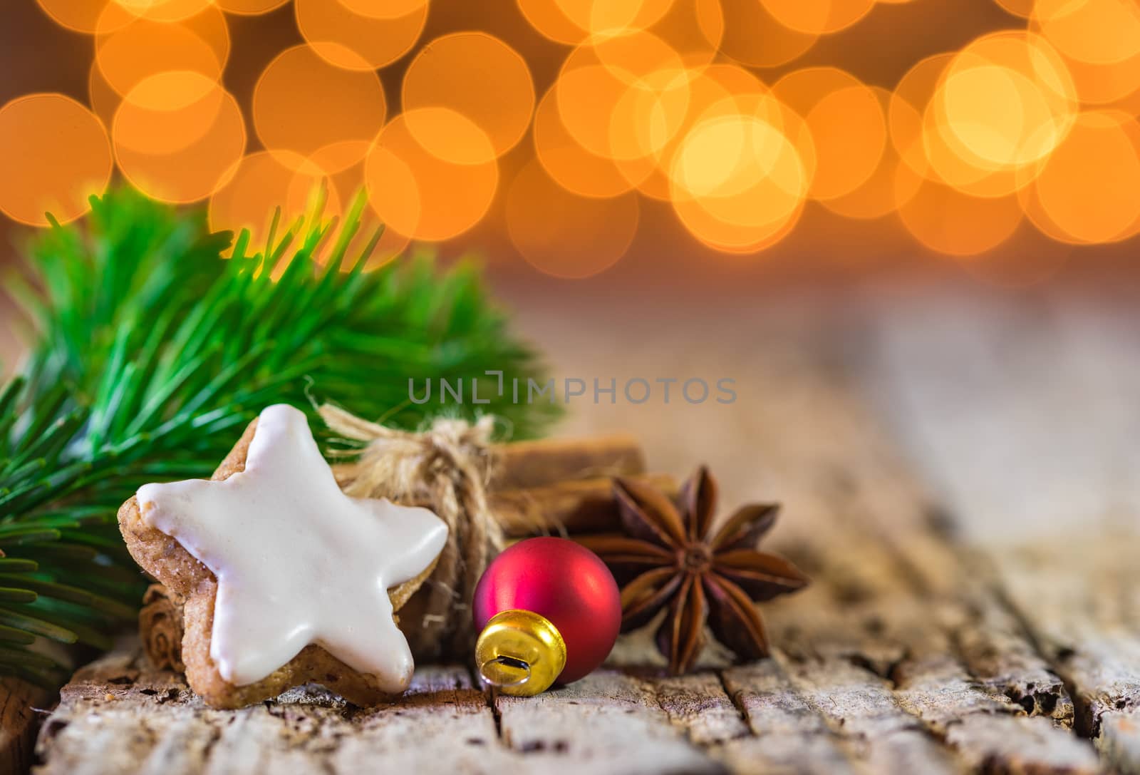 Christmas composition with star gingerbread, spices, fir branch, red ball and golden lights bokeh at background