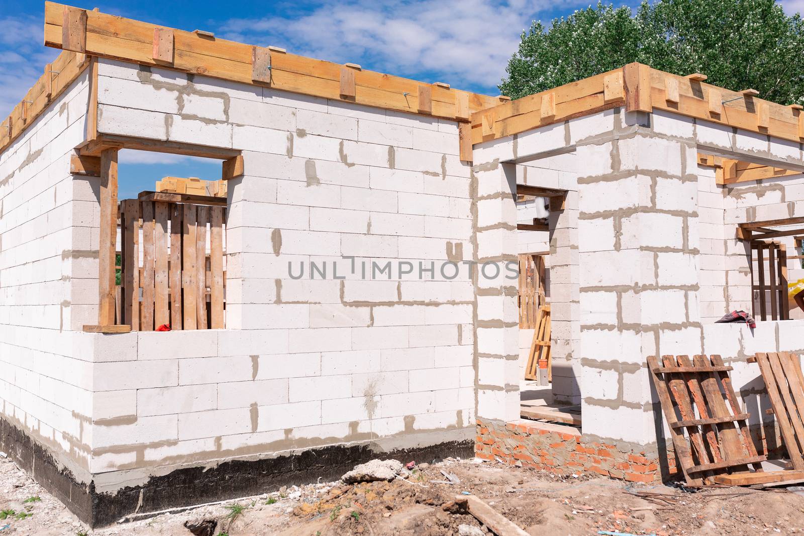 Building site of a house under construction: walls of gas concrete blocks, wooden reinforcement of windows and concrete foundation.