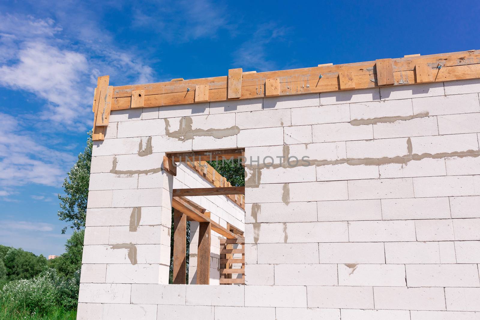 Building site of a house under construction: walls of gas concrete blocks, wooden reinforcement of windows and concrete foundation.