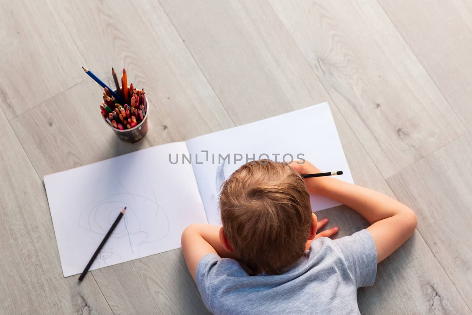 Little boy drawing with pencils on the floor in his room. Stay at home during covid 19 quarantine
