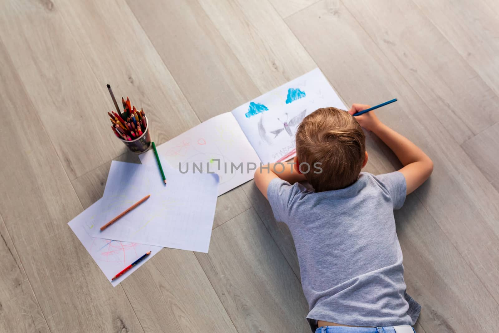 Little boy drawing with pencils on the floor in his room. Stay at home during covid 19 quarantine