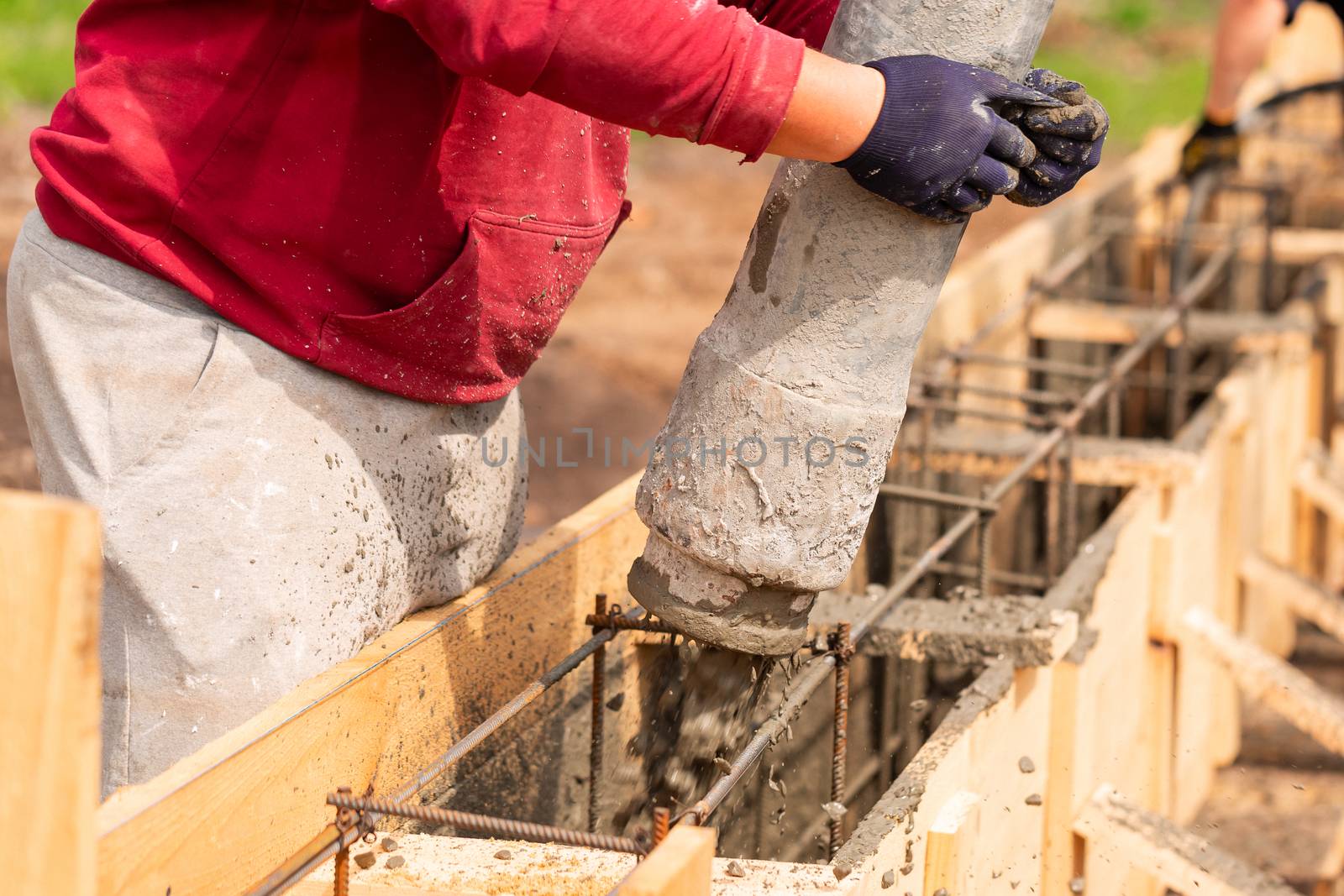 Close up of construction worker laying cement or concrete into the foundation formwork with automatic pump. Building house foundation